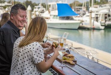 Man and woman enjoying a burger by the water