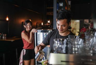 Man pouring coffee with waitress in background
