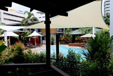 Palm City resort pool area with umbrellas and greenery