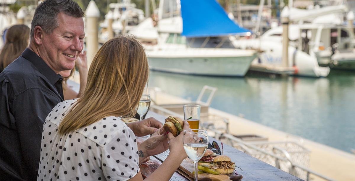Man and woman enjoying a burger by the water