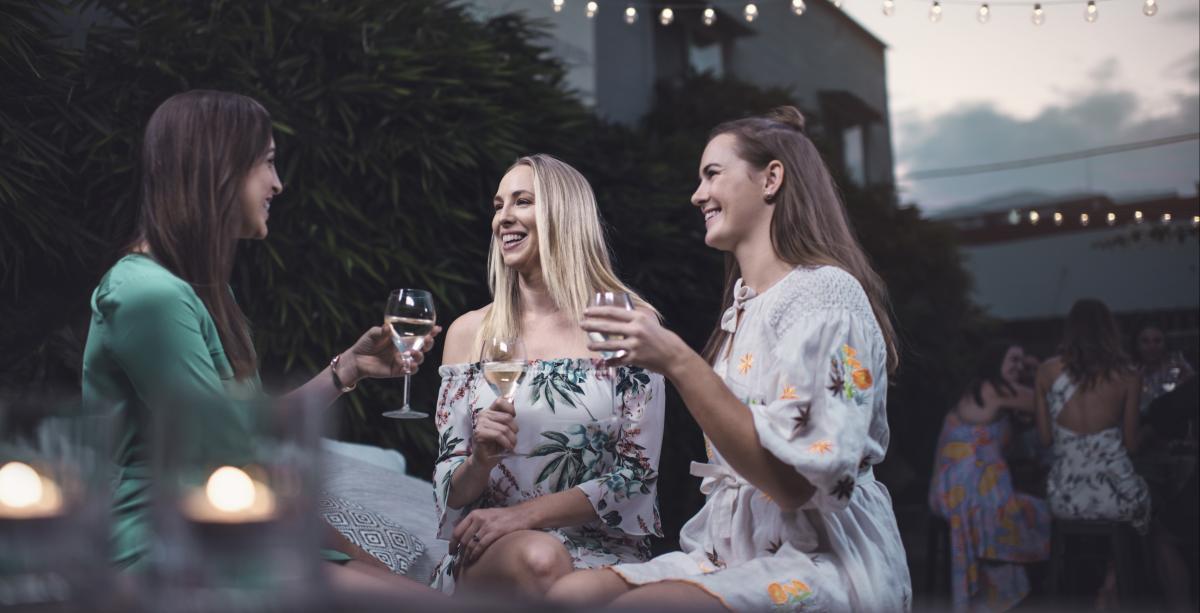 Three women enjoying a glass of wine in an alfresco setting