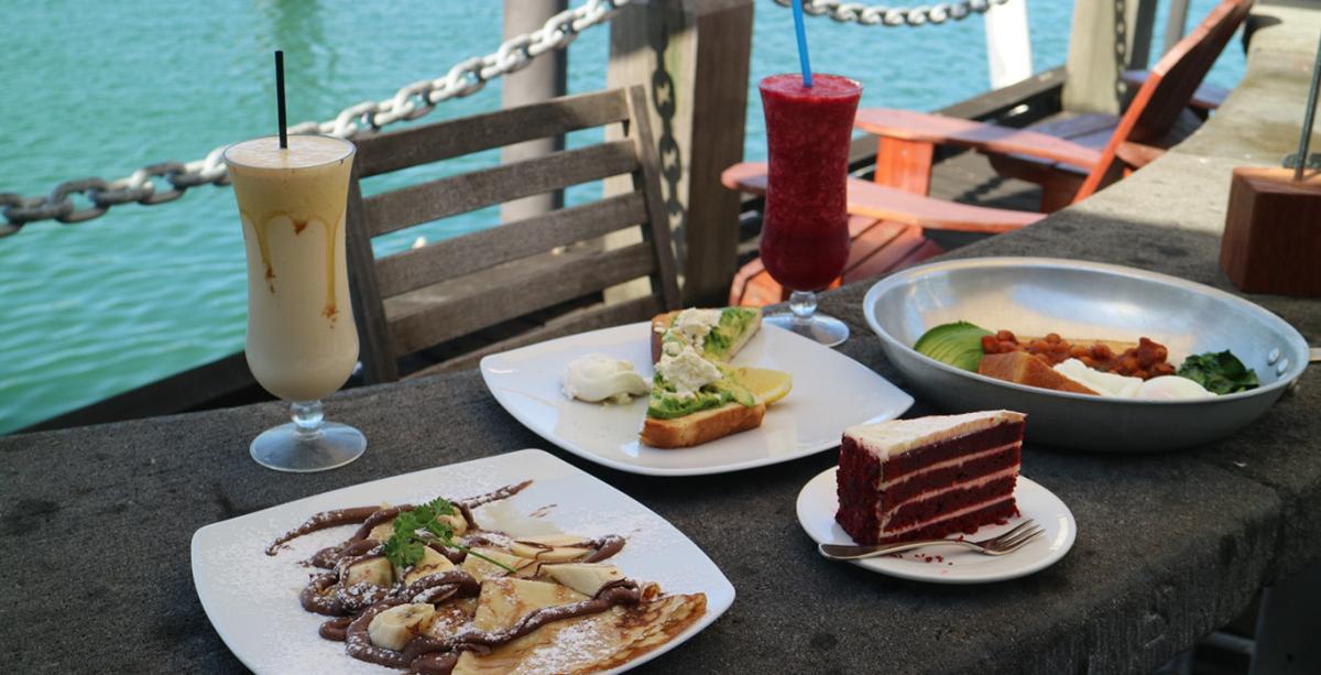 A delicious selection of food sitting on a table in a waterfront setting