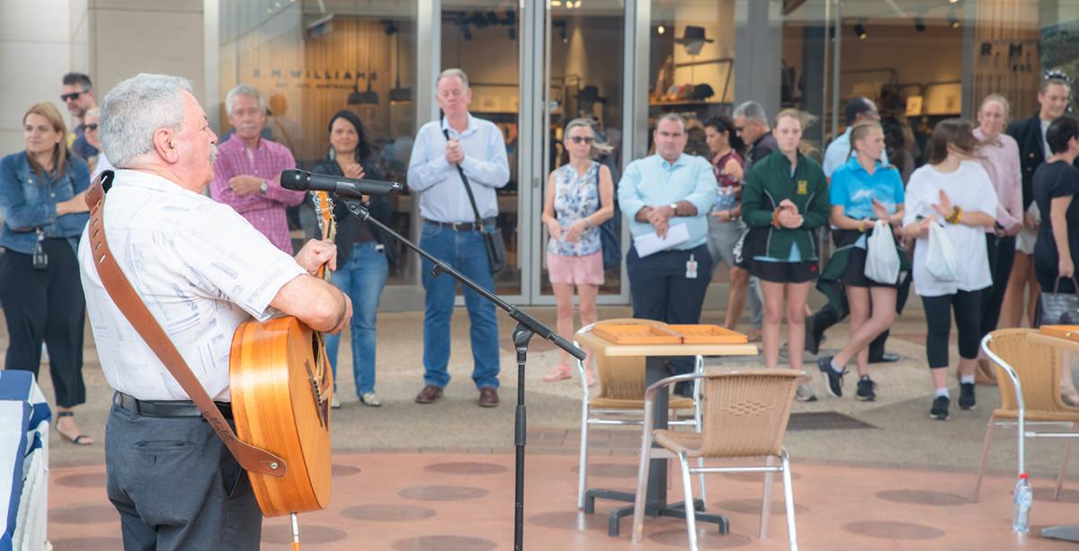 Man playing guitar with crowd watching