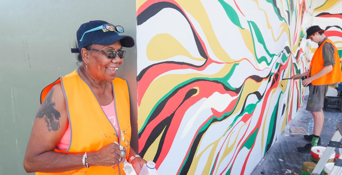 Denise Quall in front of her mural in Shadforth Lane Denise standing in front of her painting