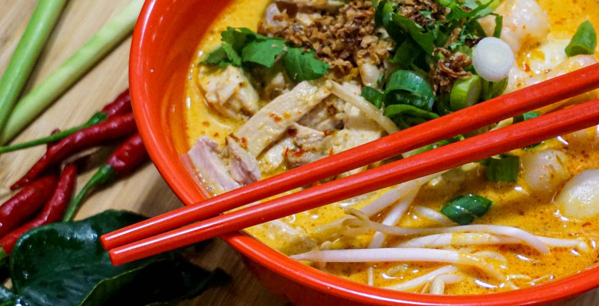 A bowl of laksa with chopsticks and spoon