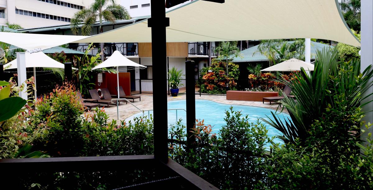 Palm City resort pool area with umbrellas and greenery