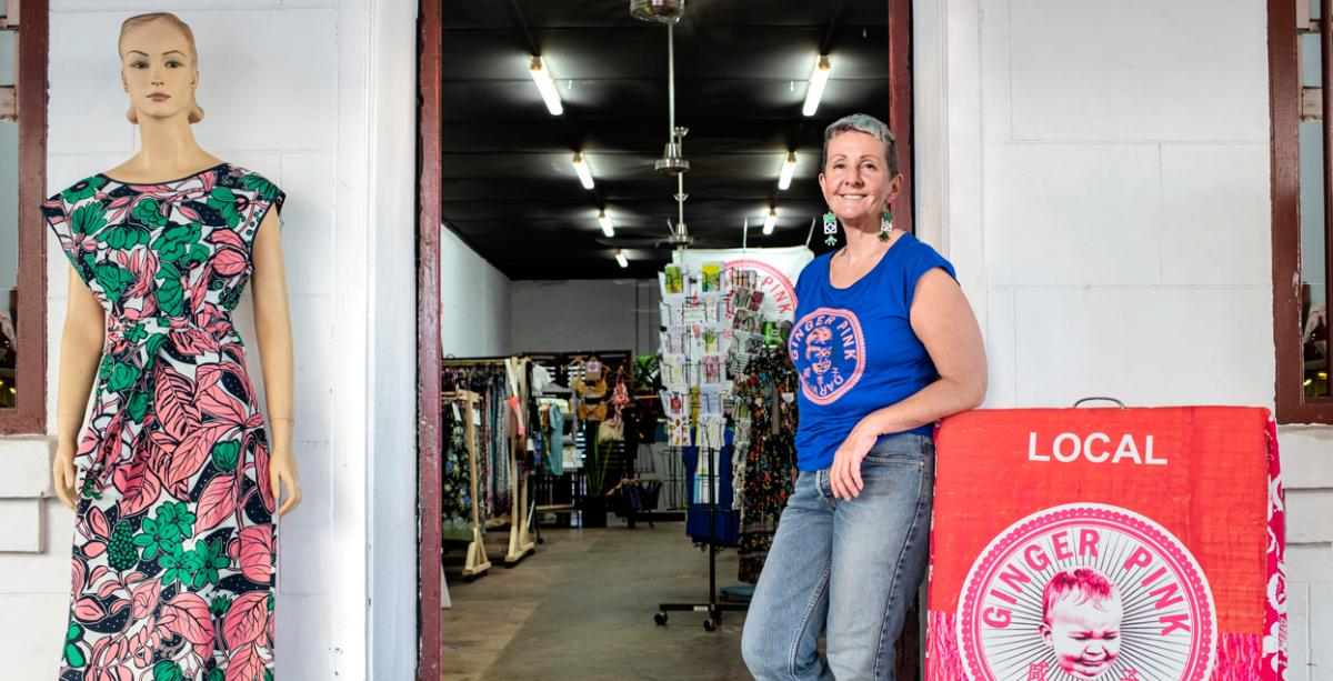 Laureen from Ginger Pink, standing next to an A-frame. A mannequin is in the foreground and her store is in the background. 