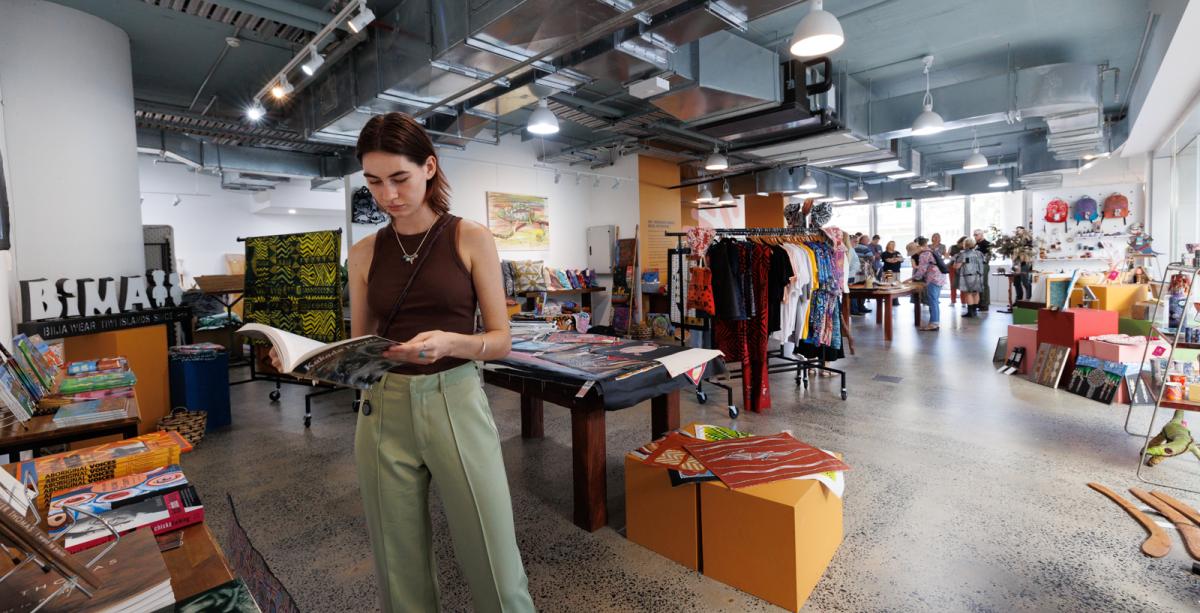 Person looking at book inside Aboriginal Bush Traders Gallery